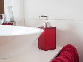 Waschbecken mit rotem Seifenspender und Handtuch im Bad