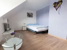 Zimmer mit Doppelbett und Glastisch unter der Dachschräge